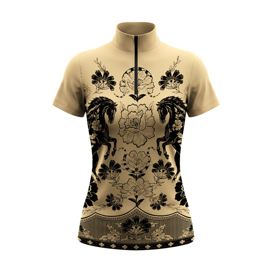 Sunlit outdoor sand equestrian arena shot of model with riding gloves standing beside white wooden jump fence wearing beige symmetrical vintage horse peony floral print short sleeve riding top