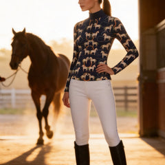 Full-body model shot beside chestnut horse in sunlit stable doorway wearing navy vintage horse hoop long sleeve riding top