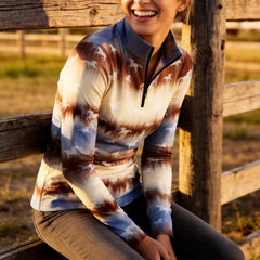 White background studio shot of rustic brown cream blue blurred tie-dye gradient repeating white running horse silhouette allover print long sleeve quarter zip riding top
