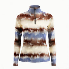 Smiling model sitting on weathered wooden ranch fence bench wearing muted western tie-dye horse silhouette long sleeve riding top in golden pasture light
