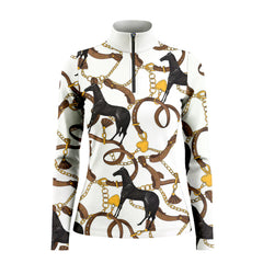 Model leaning against light grey stable wall beside chestnut horse wearing bright white heritage equestrian hardware long sleeve riding top
