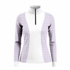 Sunset outdoor lifestyle shot of female equestrian wearing lavender side‑spliced long‑sleeve riding top with white central panel and fence‑grid geometric print