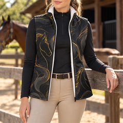 Black reversible quilted equestrian vest with gold horse head print worn in a paddock setting with a horse