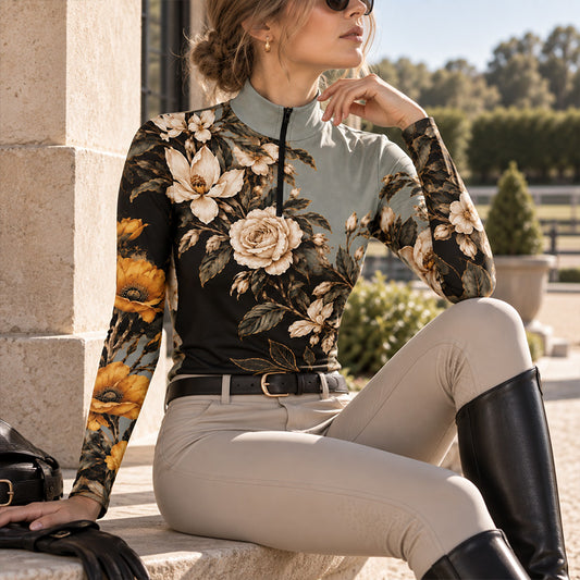 Seated rider wearing the floral riding top with beige breeches and tall boots resting on a stone barn step