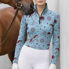 Woman in a light blue celestial horse print riding top with taupe breeches near a brown horse