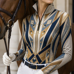 Outdoor portrait shot of female equestrian holding horse reins beside brown horse wearing navy‑gold art‑deco long‑sleeve quarter‑zip riding top