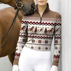 Woman wearing the Brown long sleeve quarter zip riding top with white breeches and brown leather belt while holding reins next to a chestnut horse outdoors