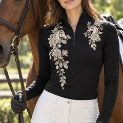 Black long sleeve quarter zip riding top with off white horse and rose artwork, styled with white high waisted riding pants near brown horses
