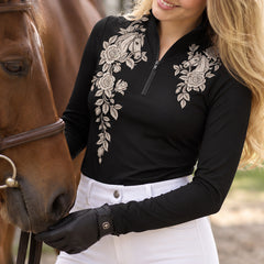 Close view of off white horse and rose print on the front of a black long sleeve quarter zip riding top