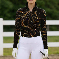 Black quarter zip riding top with gold horse line art styled with white riding breeches, white gloves and a riding crop