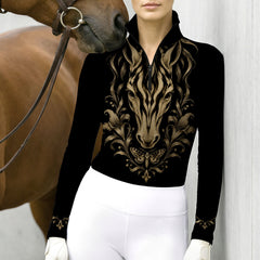 Model wearing black long sleeve quarter zip riding top with gold horse print alongside a brown horse