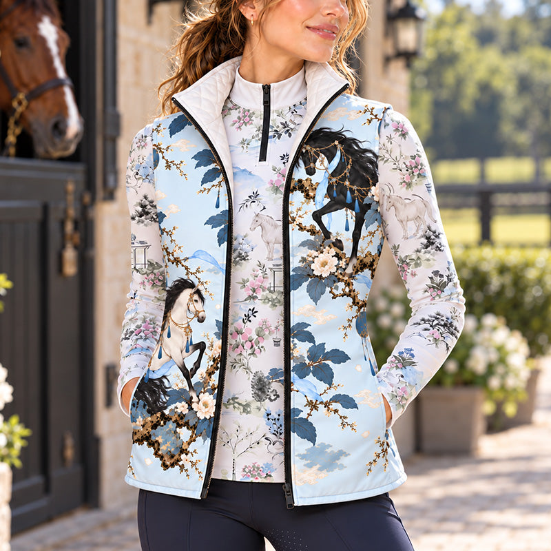 Pale blue horse and floral print quilted vest styled with dark riding pants near a stable entrance