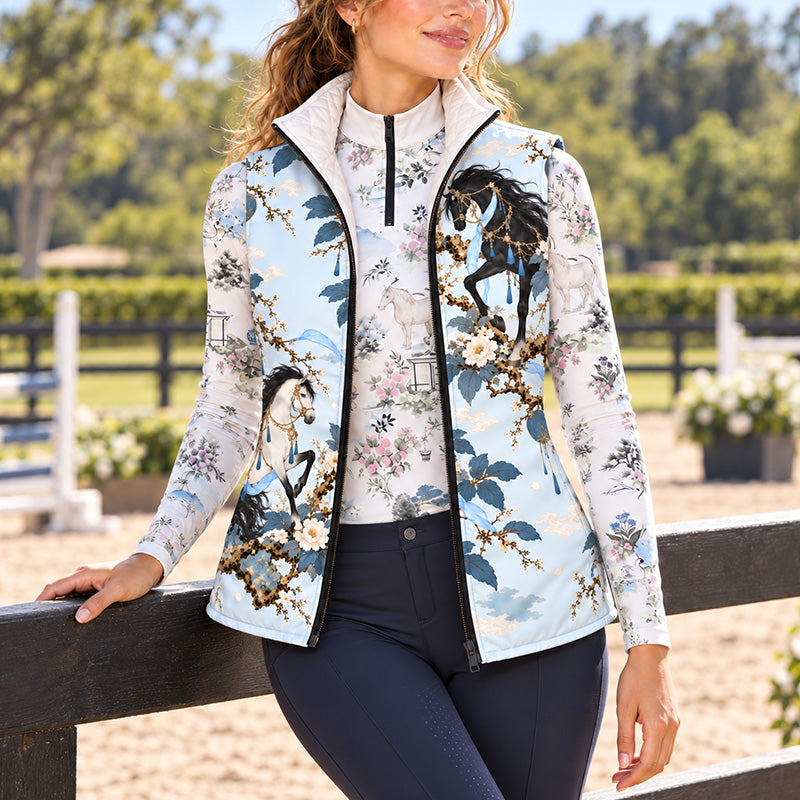 Reversible quilted equestrian vest with pale blue horse and floral print worn over a printed long sleeve quarter zip top