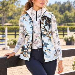 Reversible quilted equestrian vest with pale blue horse and floral print worn over a printed long sleeve quarter zip top