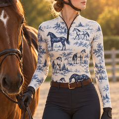 Blue print riding top styled next to a brown horse in a sunlit riding arena