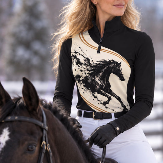 Woman wearing the black long sleeve quarter zip riding top with cream horse print panel and white riding breeches in a snowy outdoor equestrian setting
