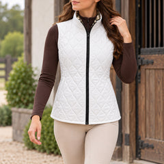 White diamond quilted side of reversible vest with side pockets, worn over a brown quarter zip top with beige riding breeches and tall boots