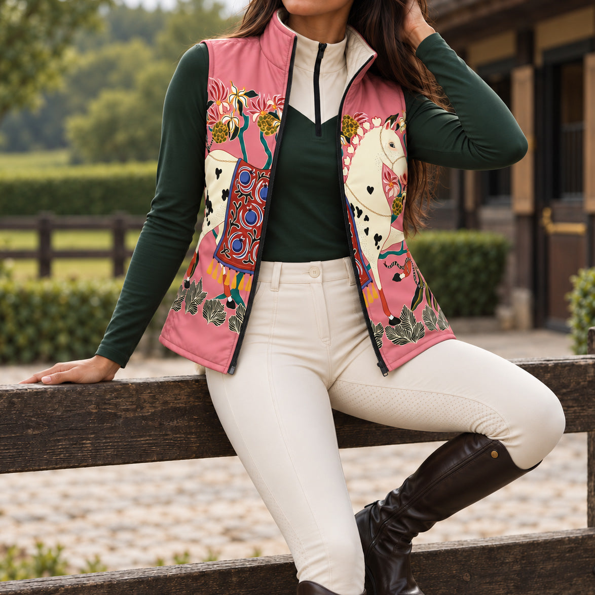 Pink horse print side of reversible quilted equestrian vest styled open over a dark green long sleeve quarter zip top and white riding breeches