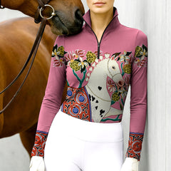 Woman wearing RIDER ATELIER artisan Dala horse dusty rose equestrian quarter-zip top at the barn with a chestnut horse