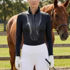Woman wearing black equestrian ghost horse portrait print long sleeve zip top standing beside a chestnut horse at the stable