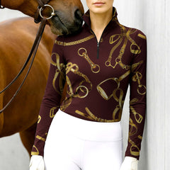 Woman standing with chestnut horse wearing burgundy equestrian tack print quarter-zip top at stable