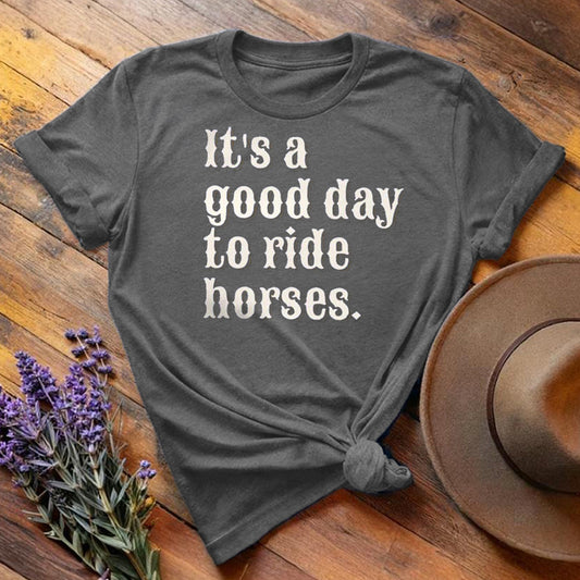 Dark gray "It's a Good Day to Ride Horses" equestrian t-shirt, flat lay on wooden background