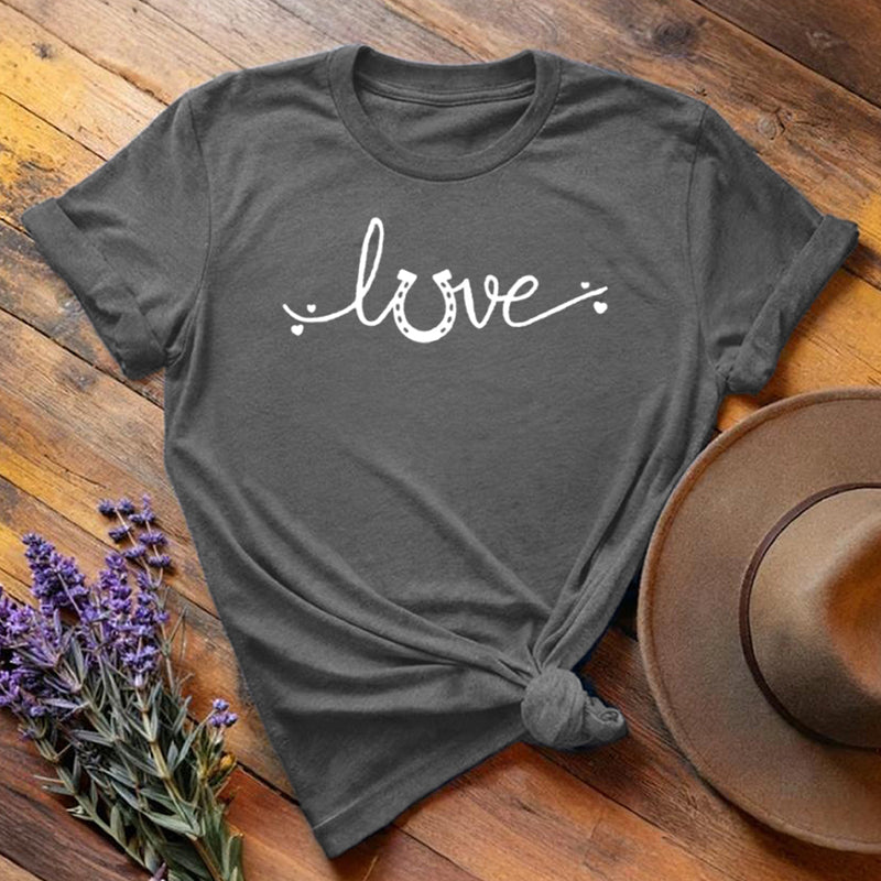 Dark gray horse shoe love equestrian t-shirt with white script print, flat lay on wooden background