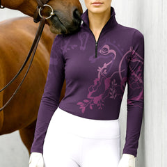 Woman wearing RIDER ATELIER floral horse silhouette plum quarter-zip top at the barn with a chestnut horse