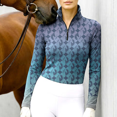 Woman wearing RIDER ATELIER gradient diamond horse head teal-purple equestrian quarter-zip top at the barn with a chestnut horse