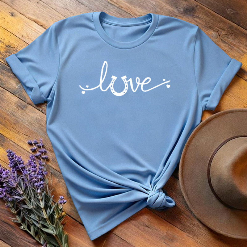 Light blue horse shoe love equestrian t-shirt with white script print, flat lay on wooden background