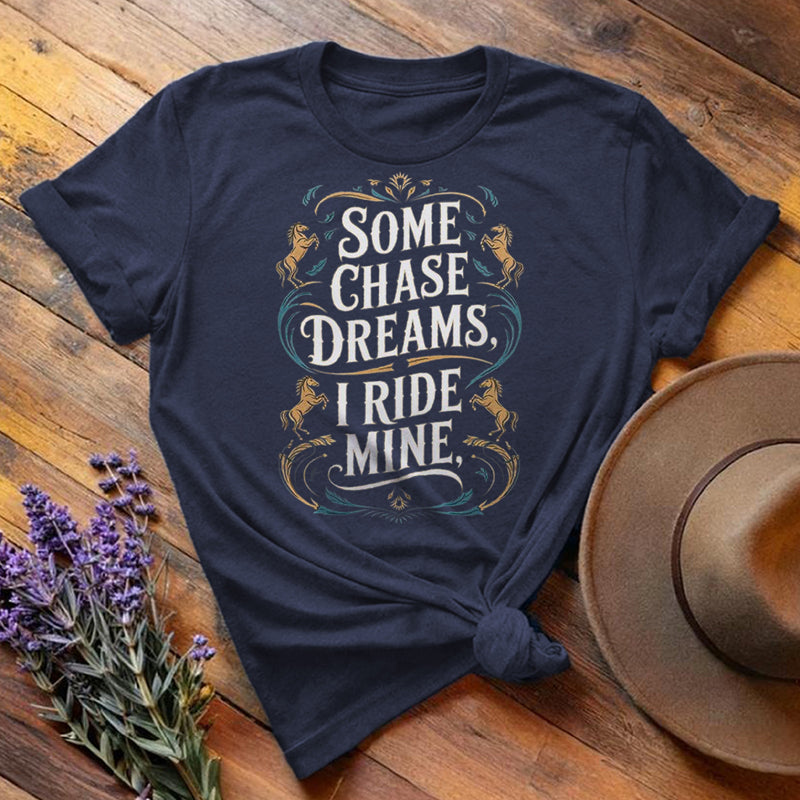 Navy blue "Some Chase Dreams, I Ride Mine" equestrian t-shirt, flat lay on wooden background