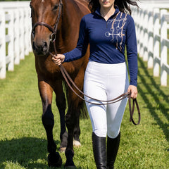 Woman walking chestnut horse while wearing navy equestrian tack bouquet print quarter-zip riding top at the arena