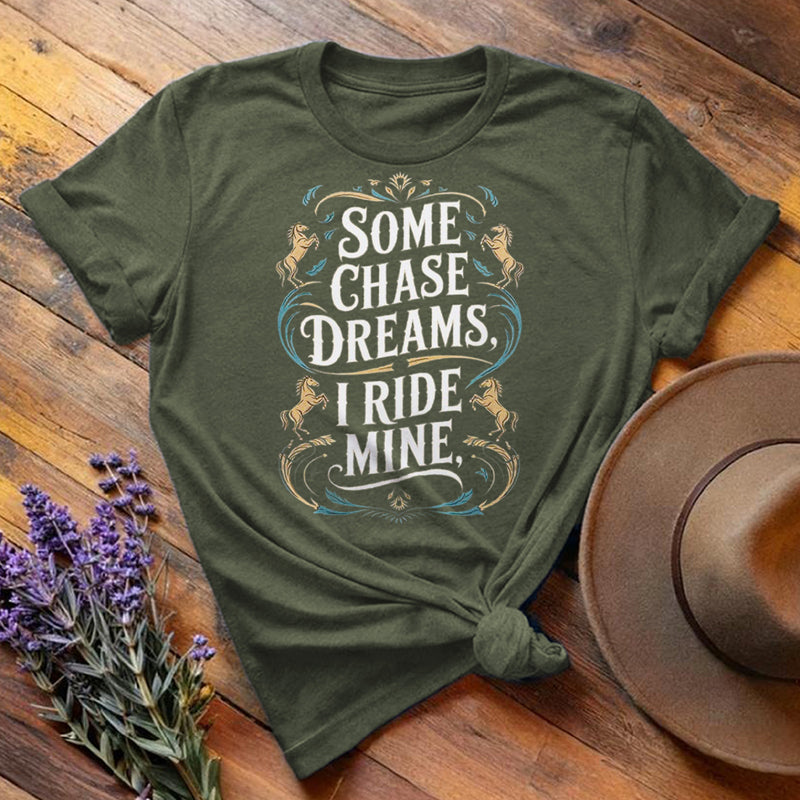 Olive green "Some Chase Dreams, I Ride Mine" equestrian t-shirt, flat lay on wooden background