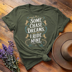 Olive green "Some Chase Dreams, I Ride Mine" equestrian t-shirt, flat lay on wooden background
