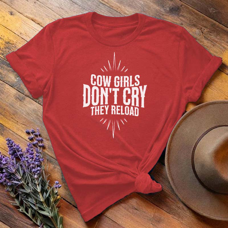 Red "Cow Girls Don't Cry They Reload" western equestrian t-shirt, flat lay on wooden background