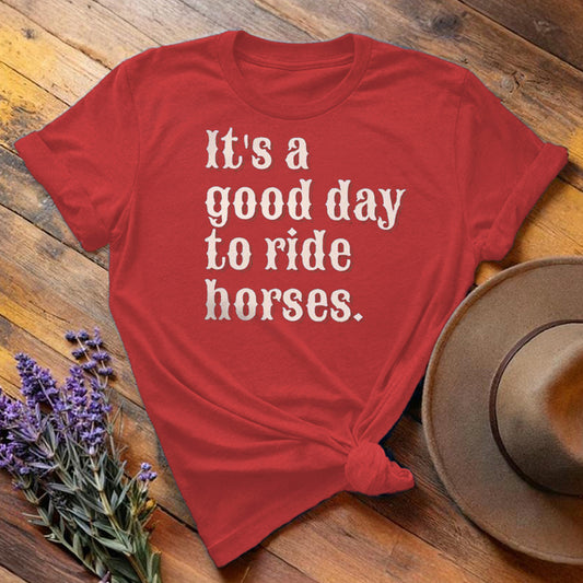 Red "It's a Good Day to Ride Horses" equestrian t-shirt, flat lay on wooden background