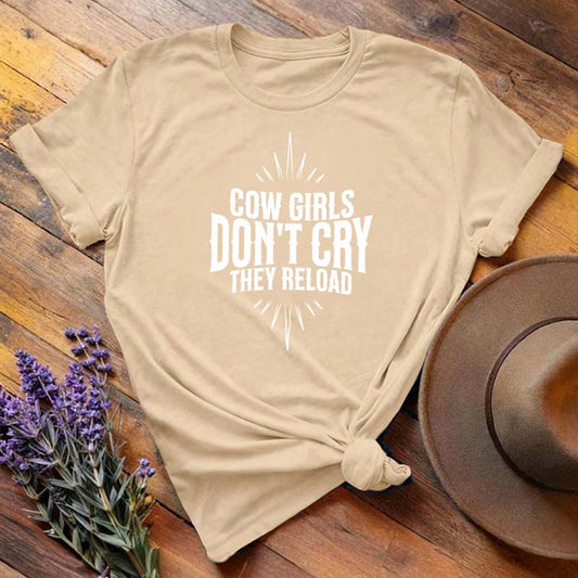 Tan "Cow Girls Don't Cry They Reload" western equestrian t-shirt, flat lay on wooden background