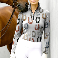 Woman standing with chestnut horse wearing watercolor horseshoe equestrian quarter-zip top at stable