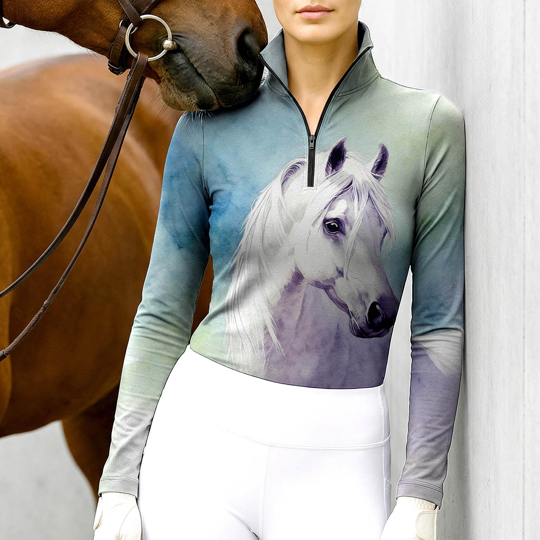 Woman wearing RIDER ATELIER watercolor white horse ombre teal-purple equestrian quarter-zip top at the barn with a chestnut horse