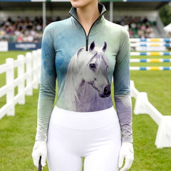 Woman wearing RIDER ATELIER watercolor white horse ombre teal-purple equestrian quarter-zip top at the show jumping arena