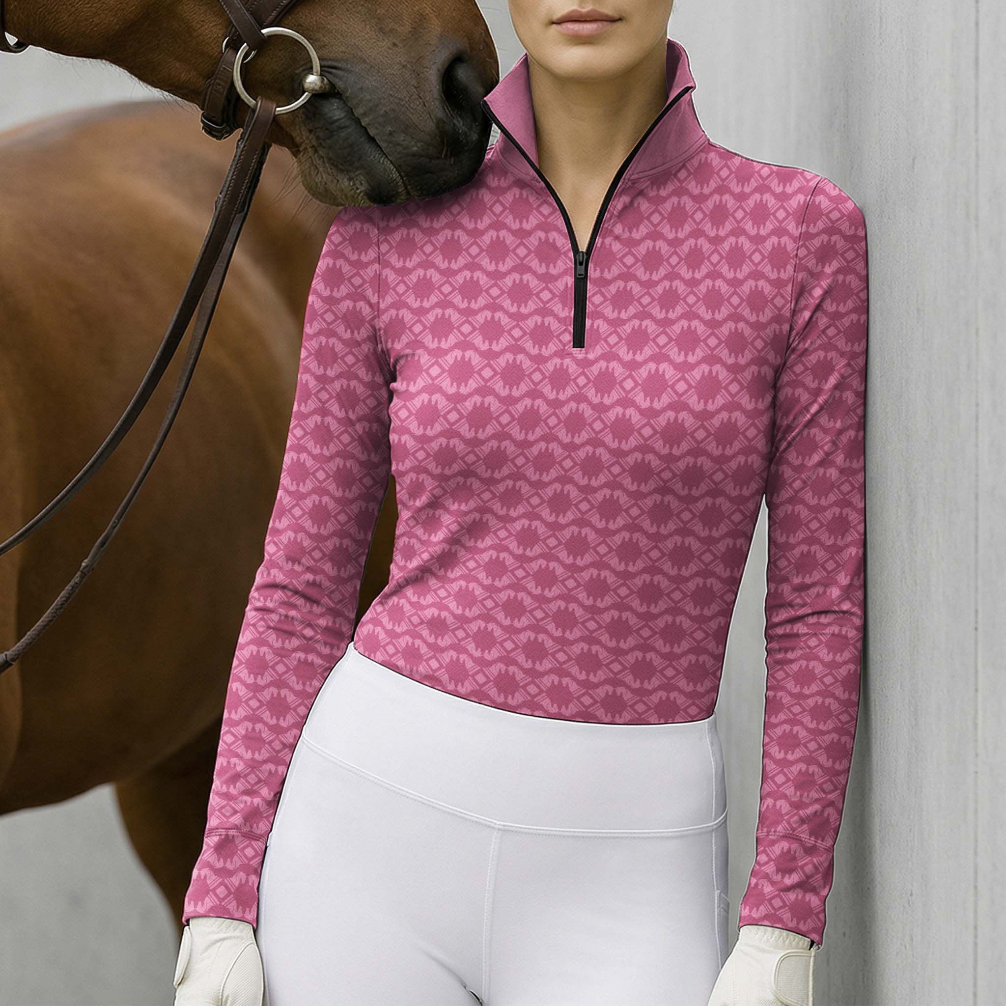 Model wearing the pink geometric print riding top with white breeches and gloves next to a brown horse